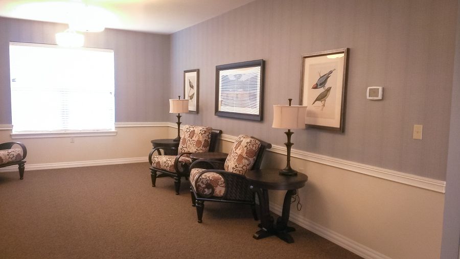 A cozy living area with two armchairs, a wooden table, and framed artwork on the walls.