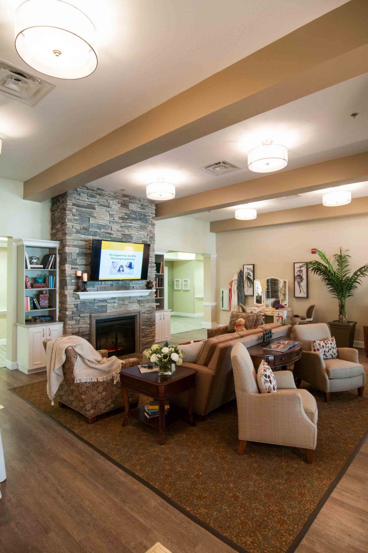 A cozy living room with a stone fireplace, comfortable seating, and a television mounted above the mantel.