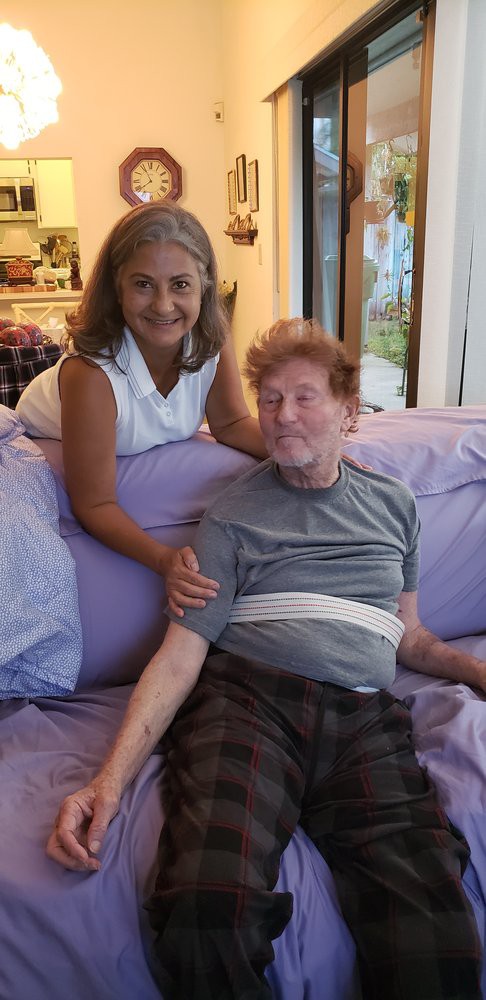 A woman and a man sitting together on a couch, smiling at the camera.