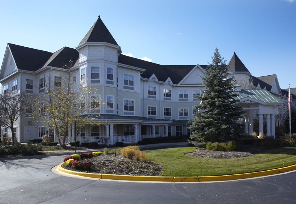 A large, white multi-story building with a turret and landscaped grounds.