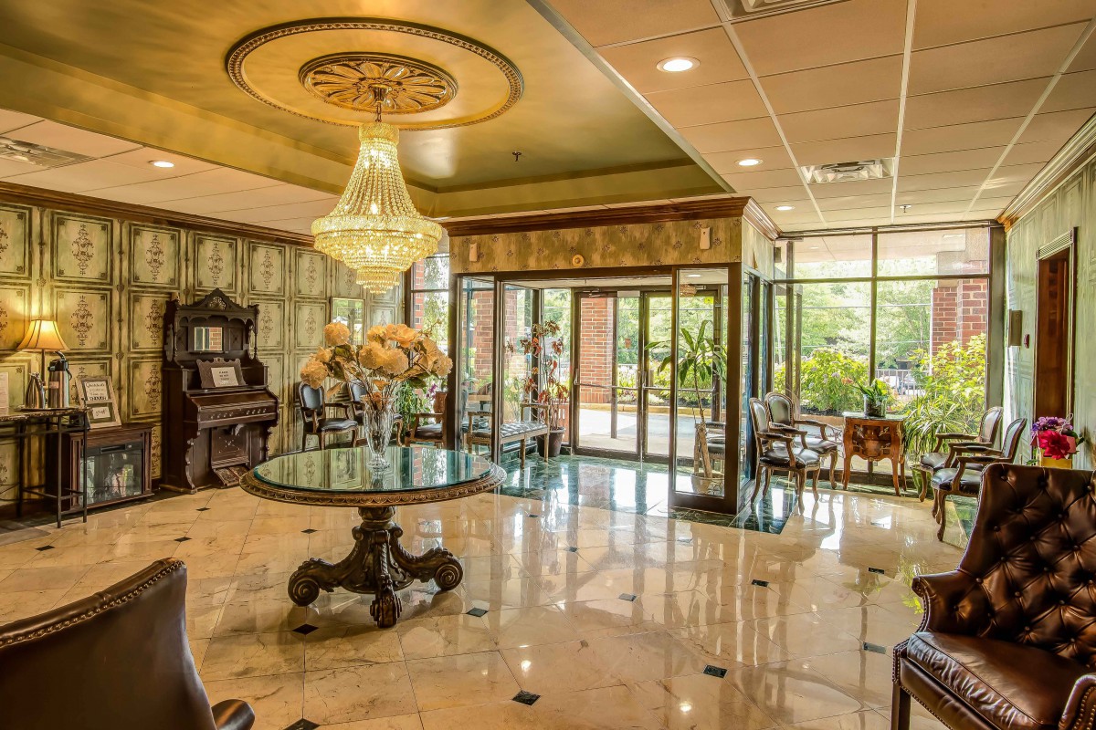 A luxurious hotel lobby with an elegant chandelier and marble flooring.