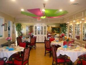A well-decorated dining room with colorful ceiling drapery and elegantly set tables.