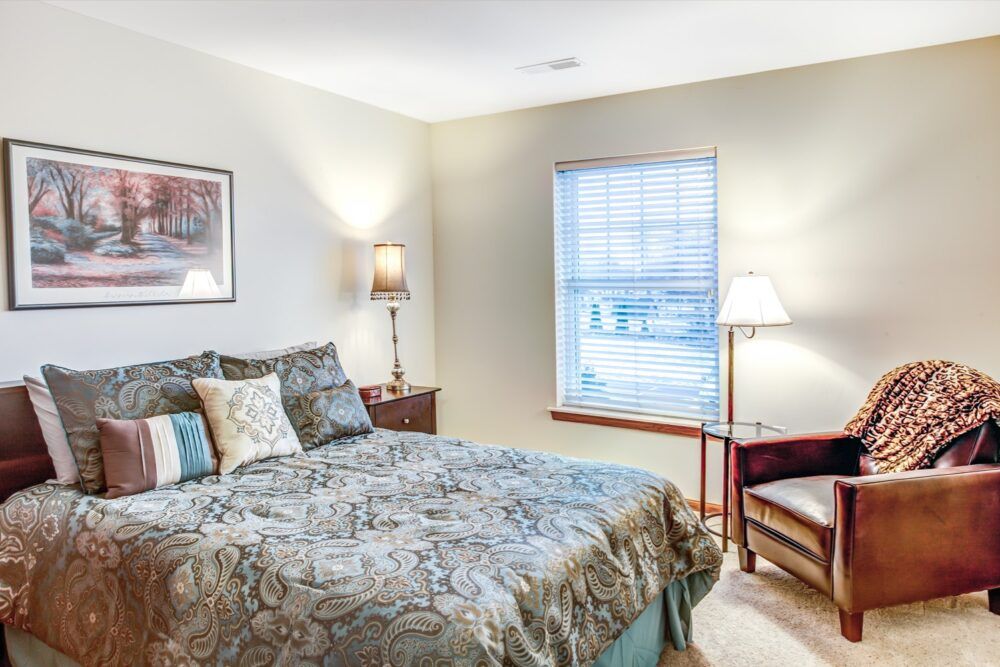 A cozy bedroom with a comfortable bed, soft lighting, and a window letting in natural light.