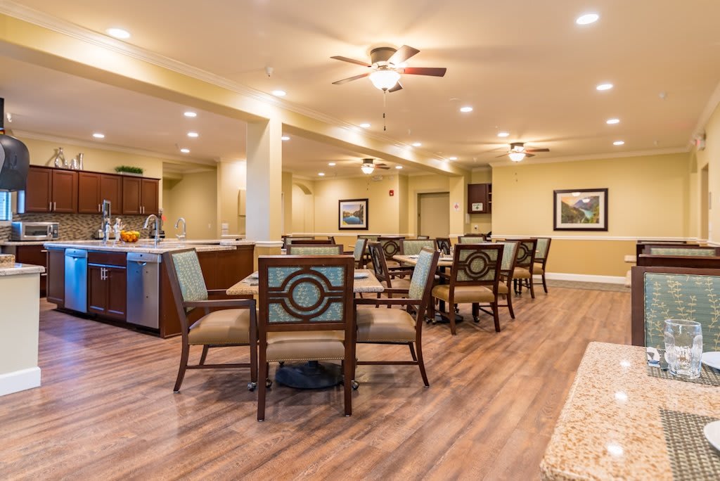 A well-lit dining area with multiple tables and chairs, featuring a wooden floor and cozy interior design.