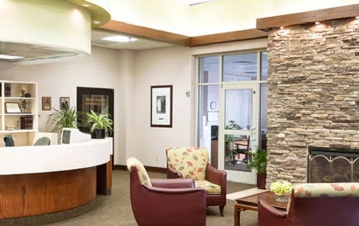 A cozy waiting room with comfortable chairs and a stone accent wall.