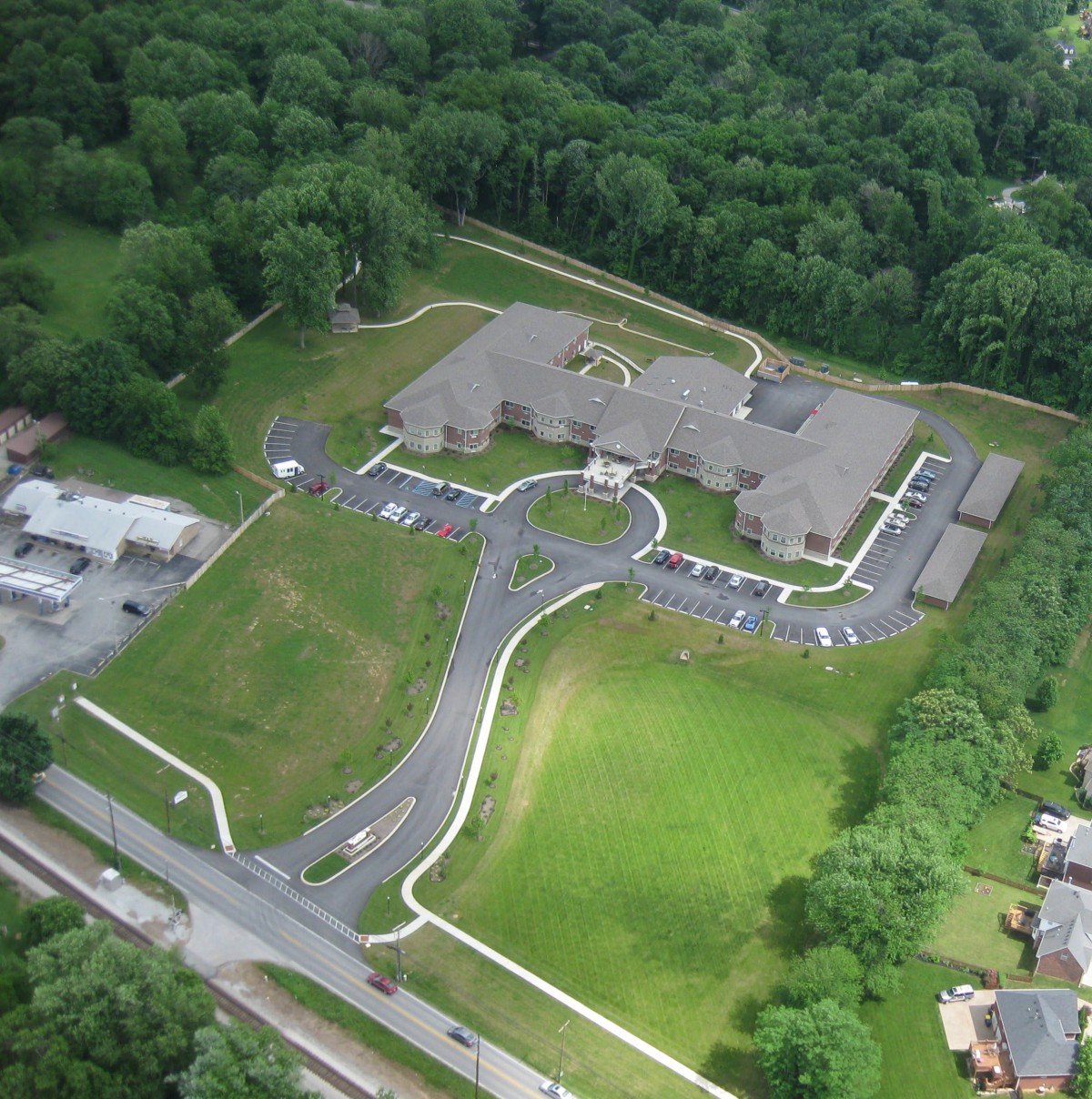 Aerial view of a large building complex surrounded by greenery and a parking area.