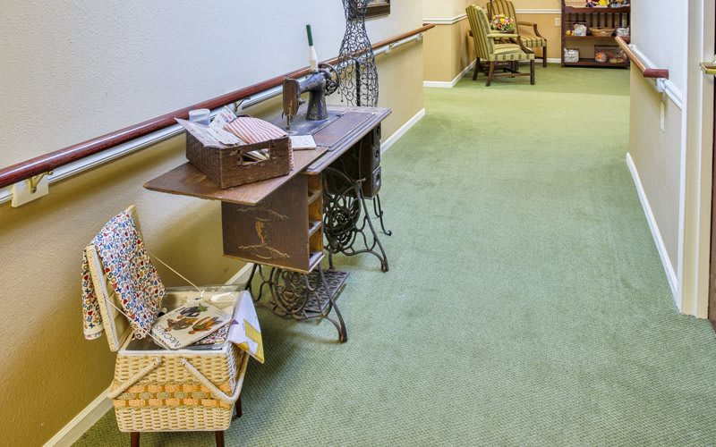 A hallway with vintage furniture and a green carpet, featuring a wooden desk and seating area.