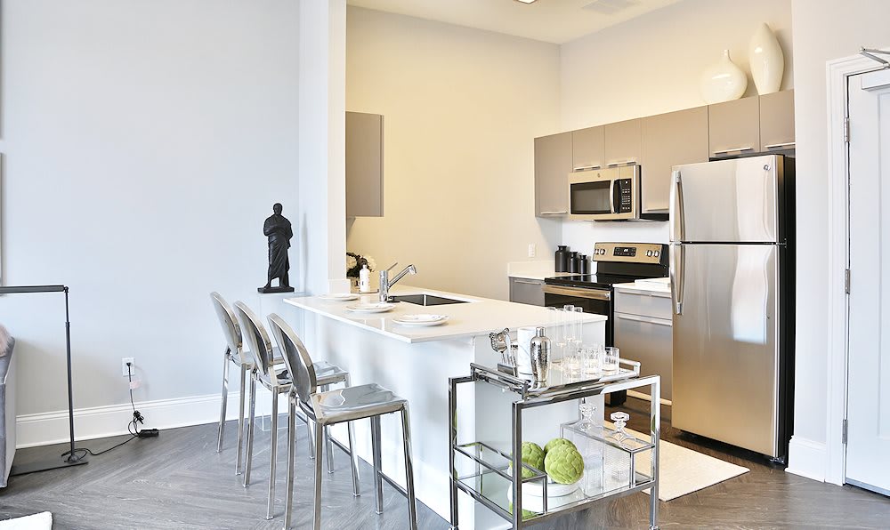 A modern kitchen with a sleek island counter, stainless steel appliances, and contemporary bar stools.