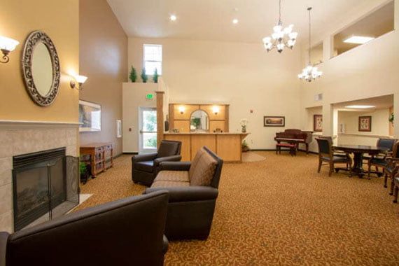 A hotel lobby with comfortable seating and a reception desk under elegant chandeliers.