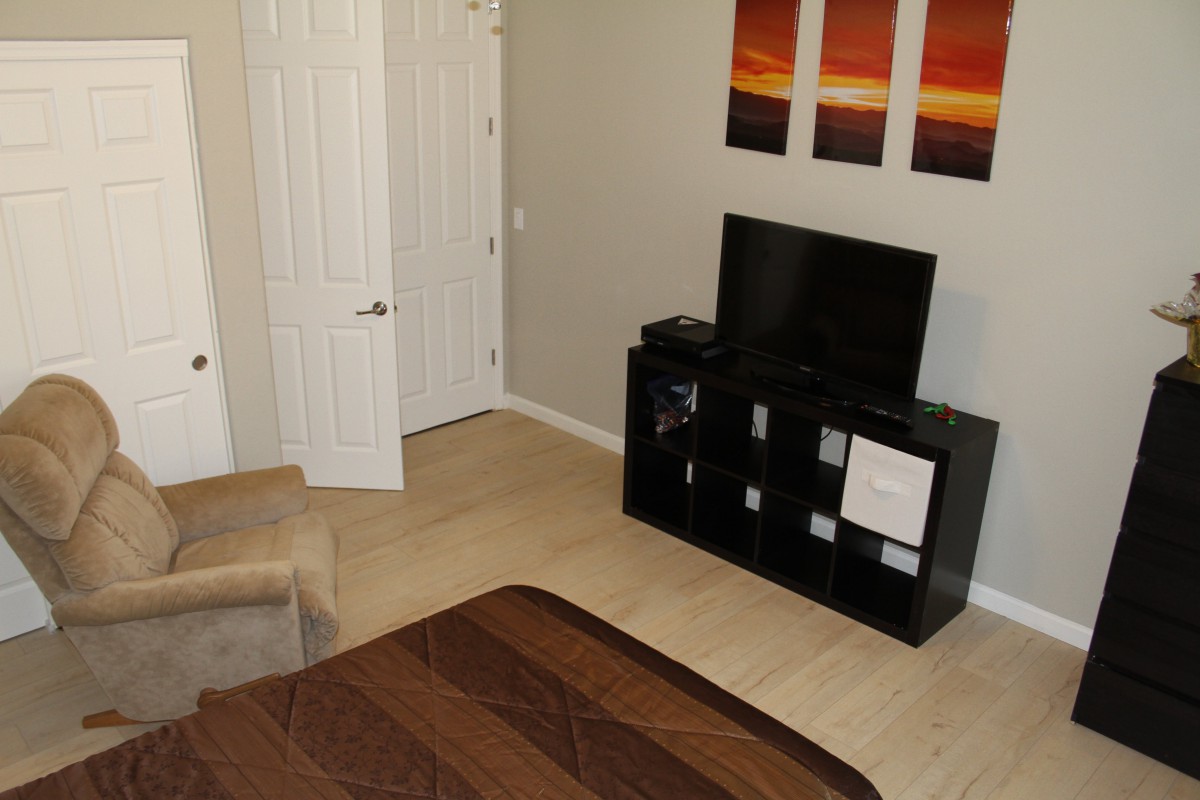 A modern bedroom interior with a TV stand and decorative artwork.