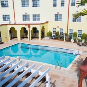 A hotel courtyard featuring an outdoor swimming pool surrounded by a yellow building.
