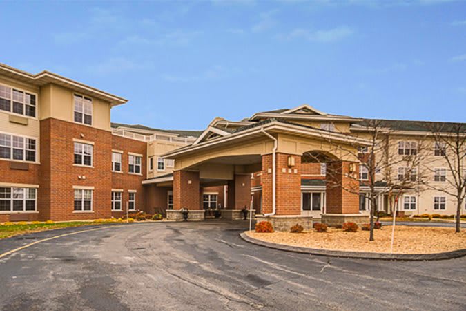 A large brick residential facility with a covered entrance and a circular driveway.