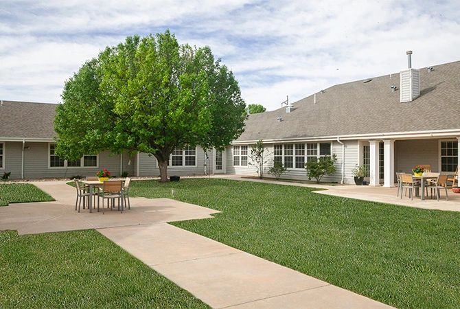 A suburban residential house with a well-maintained lawn and a large tree in the backyard.