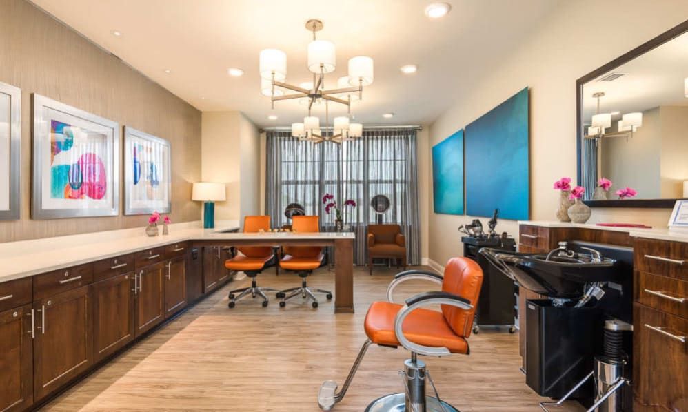 A modern office space featuring orange chairs, stylish lighting fixtures, and contemporary artwork on the walls.