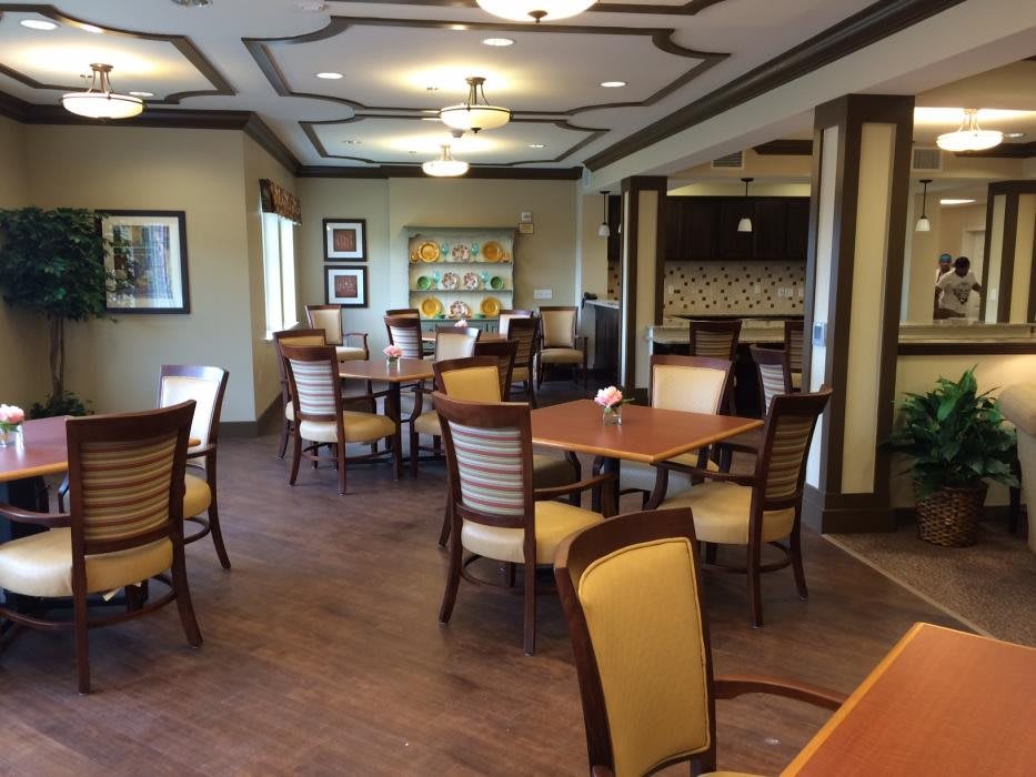 A cozy dining area with several tables and chairs, warmly lit with ceiling lights.