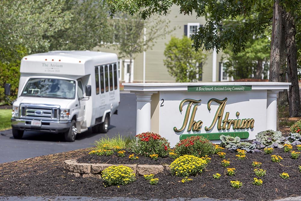 A shuttle bus parked near a landscaped sign for 'The Atrium'.