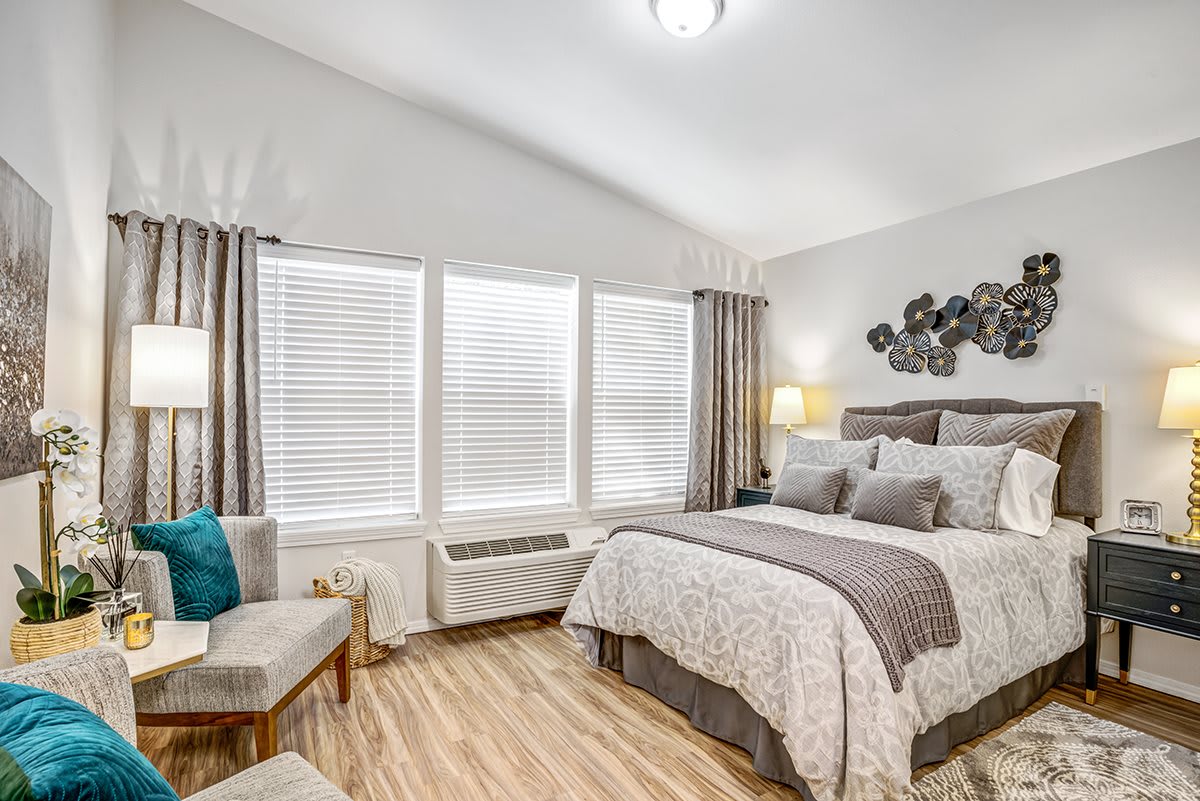 A modern bedroom with stylish decor, featuring hardwood floors and large windows that let in natural light.