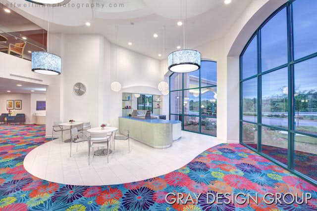 A modern and bright cafe interior with colorful carpet and large windows.