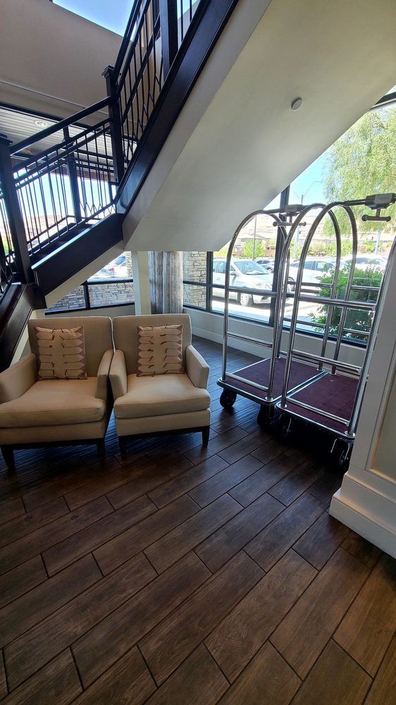 A cozy hotel lobby corner with armchairs and a luggage cart near large windows.