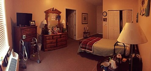 A cozy bedroom with a neatly made bed and a dresser with a mirror.