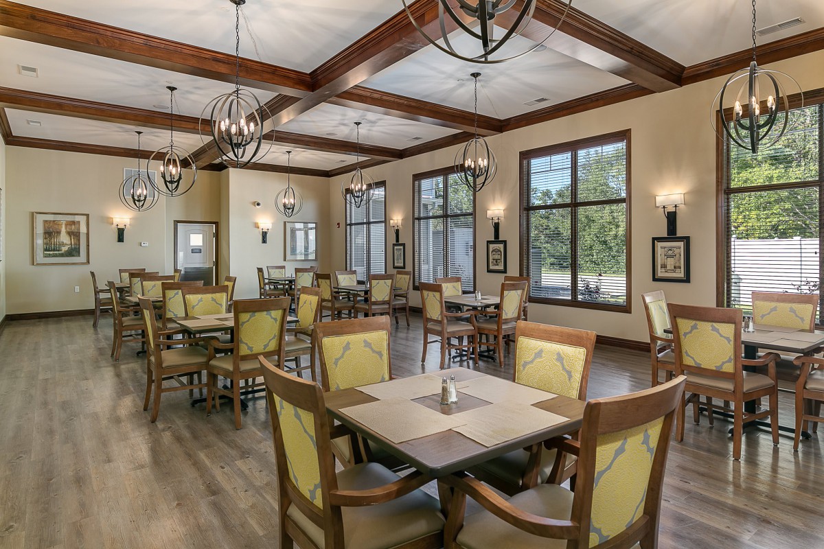 A modern dining area with wooden beams, ample seating, and natural lighting.