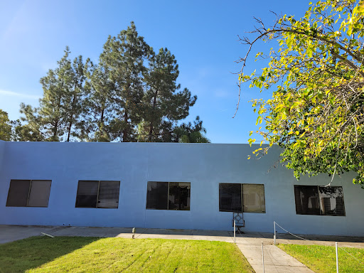 A serene view of a blue building surrounded by trees and a well-manicured lawn.