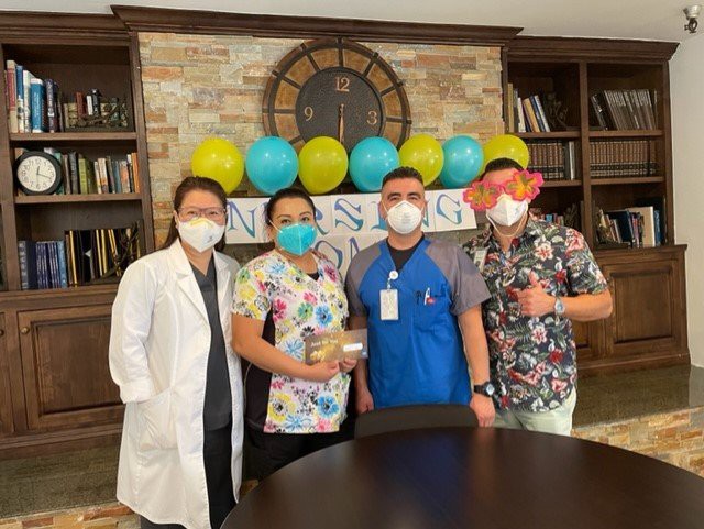 A group of healthcare workers celebrating with balloons and wearing masks.