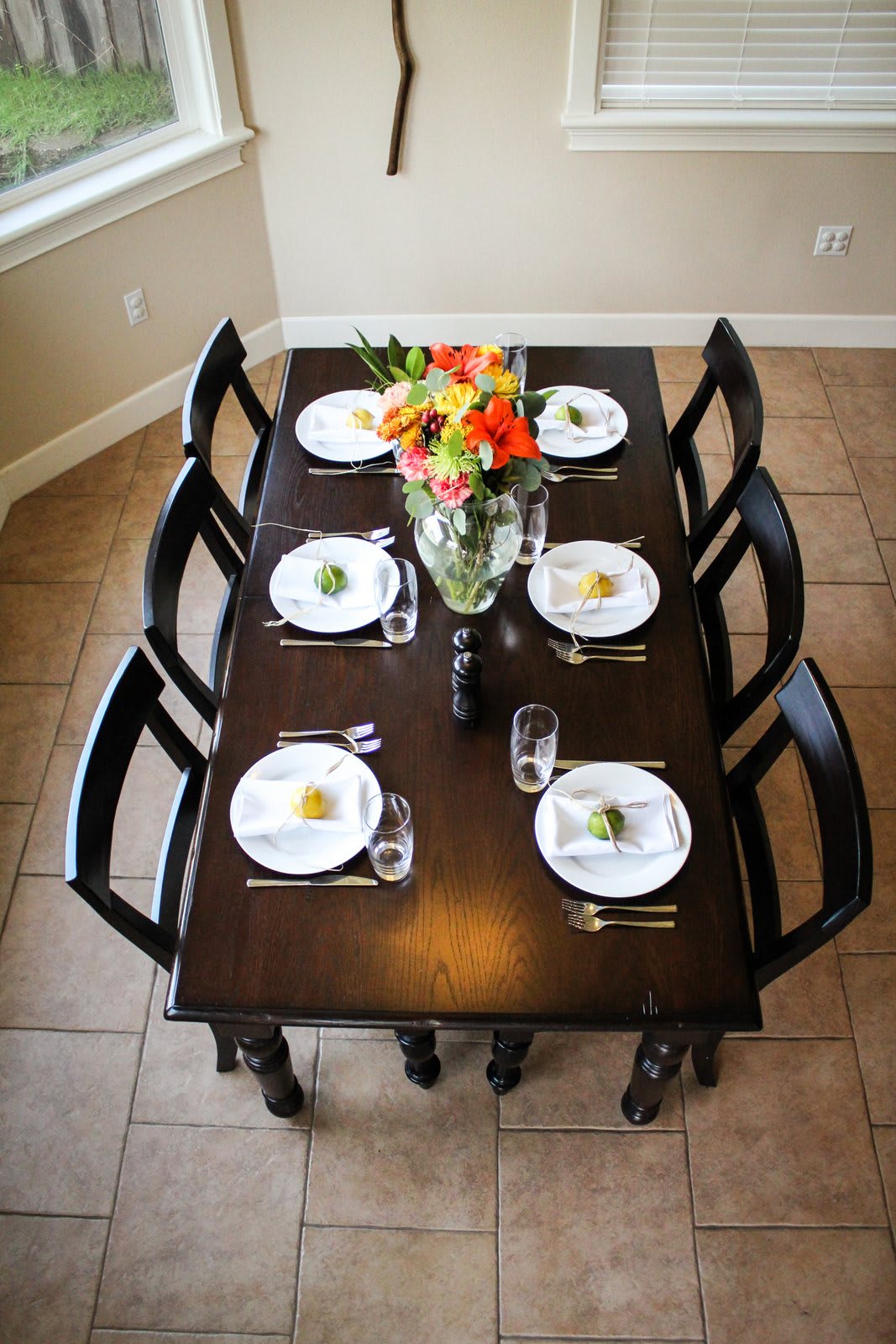A dining table set for six people with elegant white plates, cutlery, and a floral centerpiece.