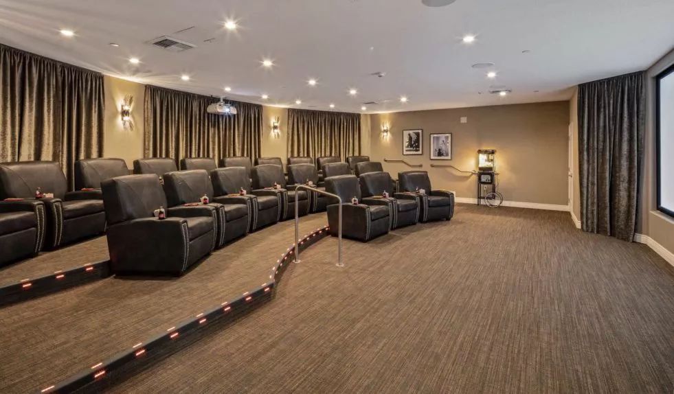 A cozy home theater with recliner seating arranged in rows facing a large screen.