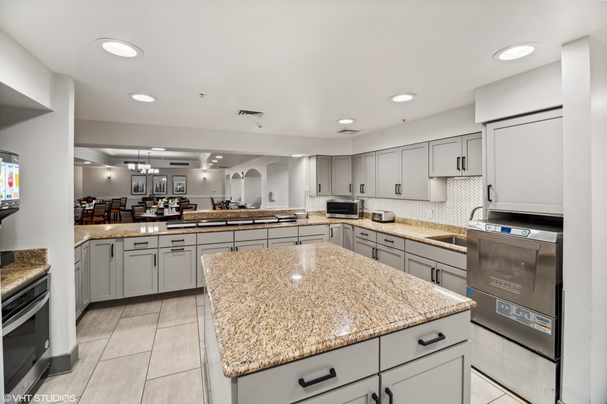 A spacious, modern kitchen featuring a large granite island and ample cabinetry.