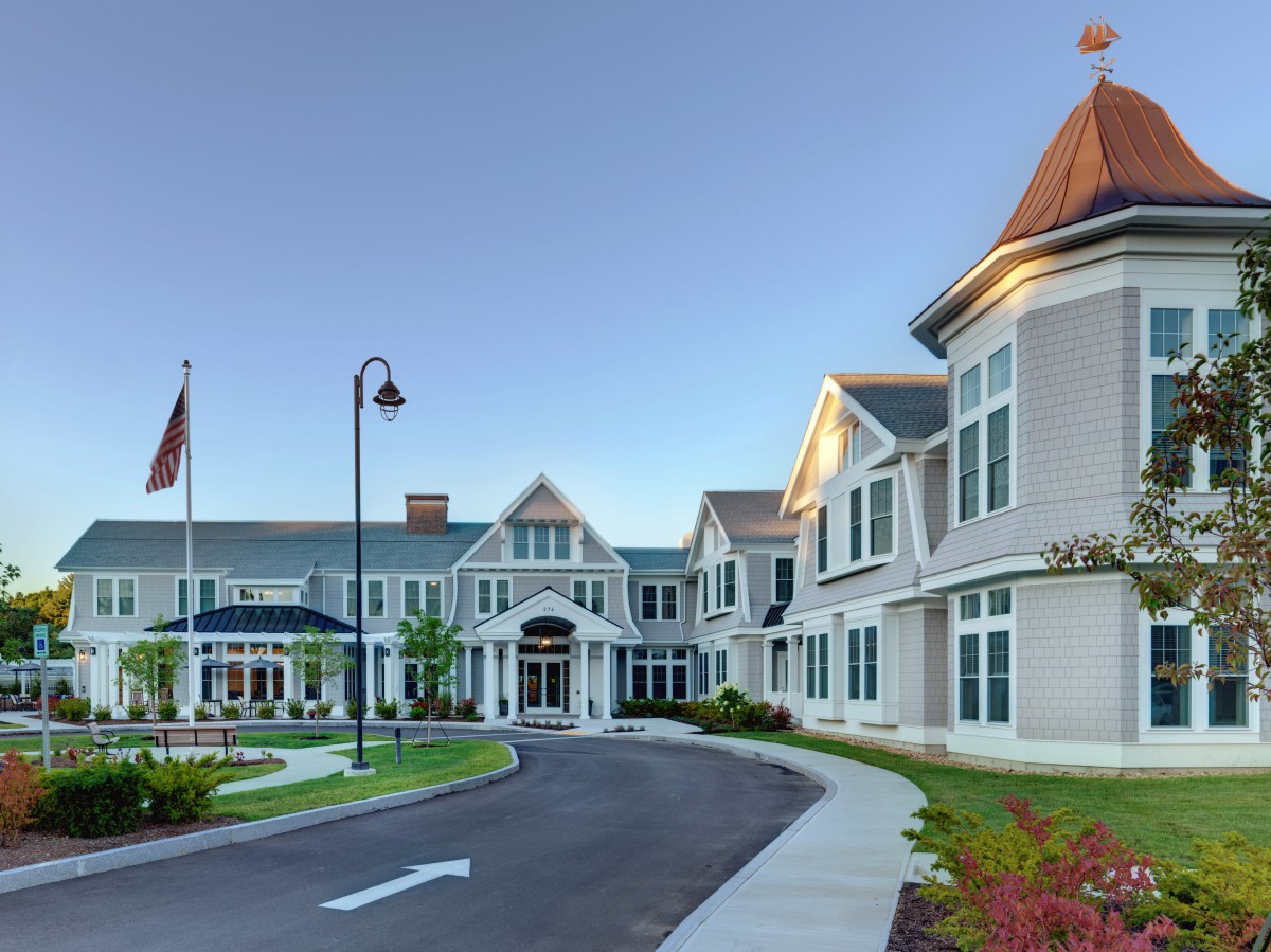 A large residential-style building with a circular driveway and flags at the entrance.