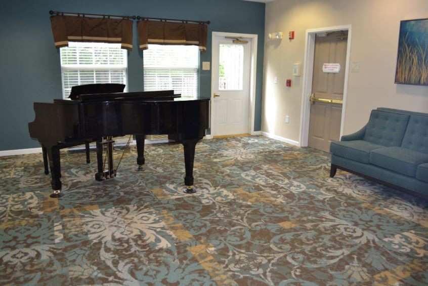 A cozy room featuring a grand piano and comfortable seating.