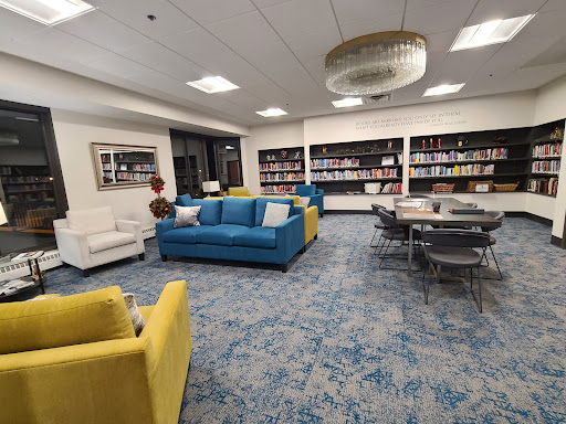 A vibrant and modern library interior featuring colorful couches and a well-stocked bookshelf.