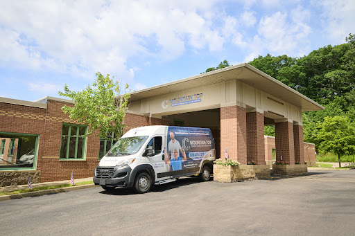A delivery van parked in front of a modern building under a partly cloudy sky.