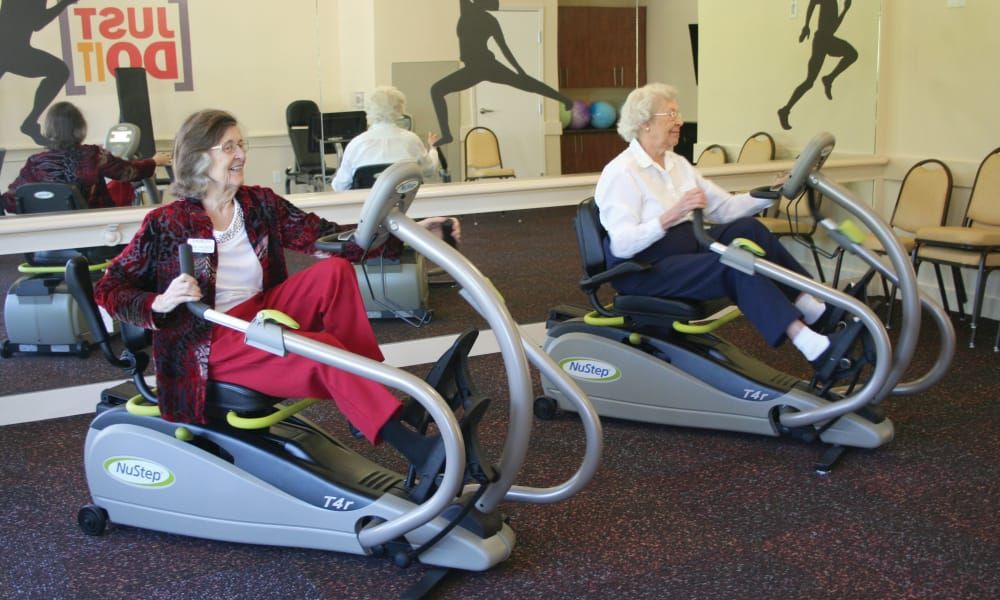 Seniors exercising on fitness machines in a gym.