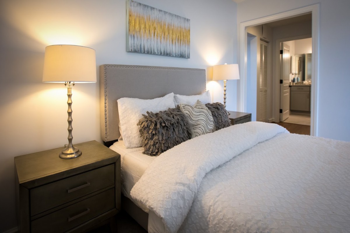 A modern bedroom with a comfortable bed adorned with fluffy pillows and warm lighting from bedside lamps.
