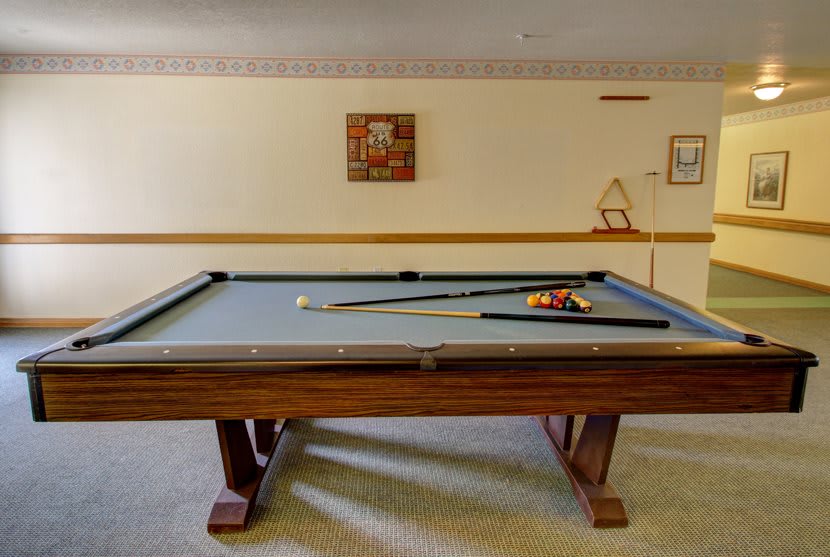 A pool table with cue sticks and balls in a game room.