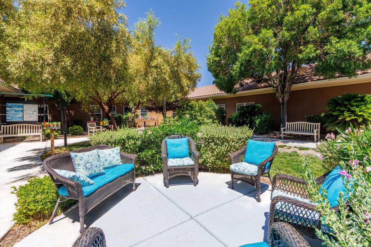 A serene outdoor patio area with wicker furniture and lush greenery.