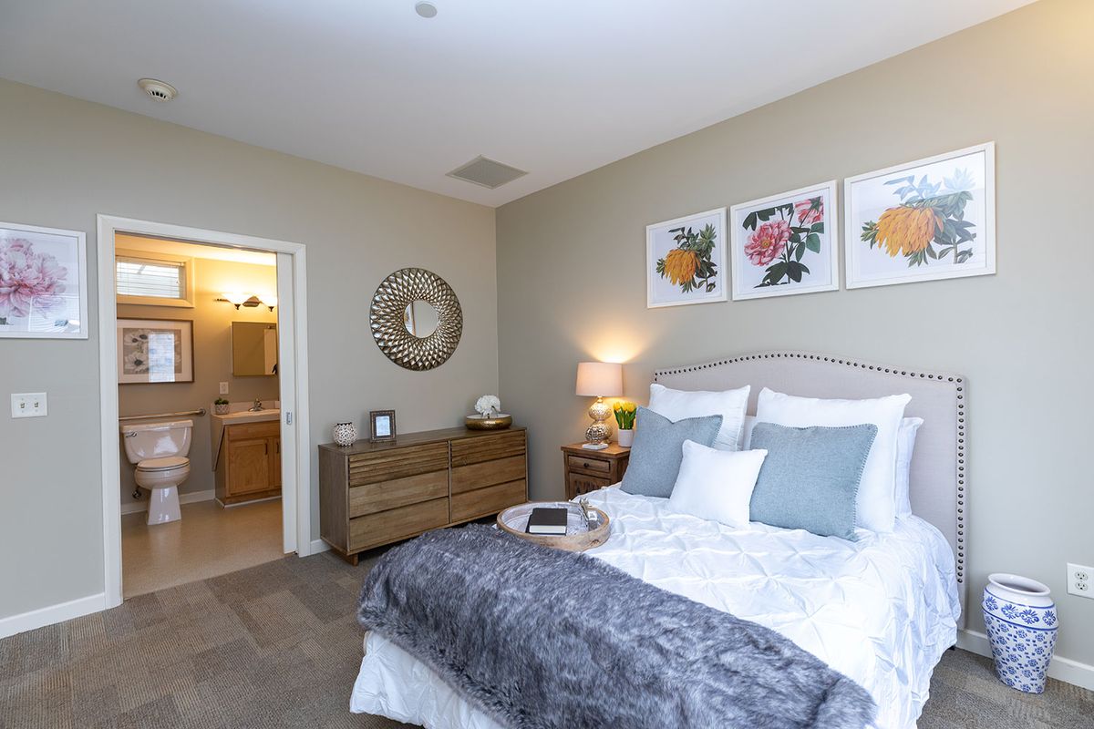 A well-decorated bedroom with a cozy bed, stylish artwork, and soft lighting.