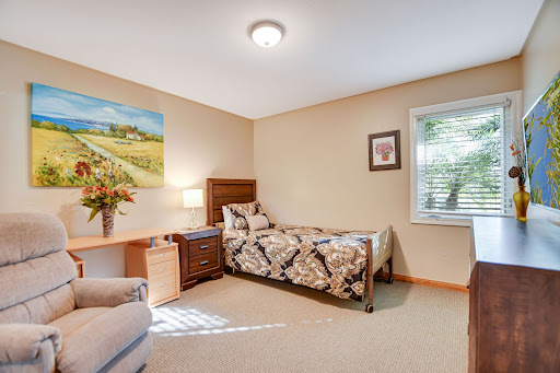 A cozy and well-lit bedroom featuring a single bed, a decorative quilt, and a touch of nature with artwork on the wall.
