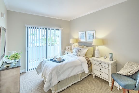 A cozy and well-decorated bedroom featuring a comfortable bed, two lamps on nightstands, and light-colored decor.