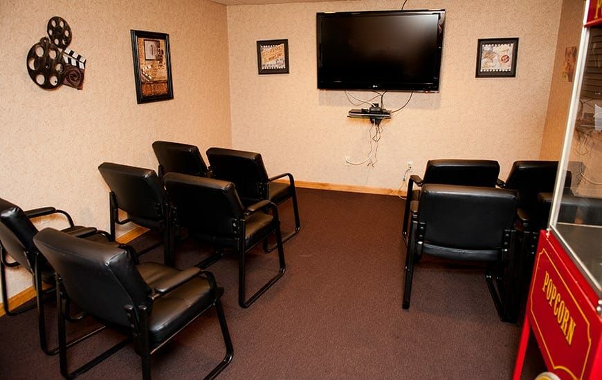 A small waiting room with chairs arranged in front of a wall-mounted television.
