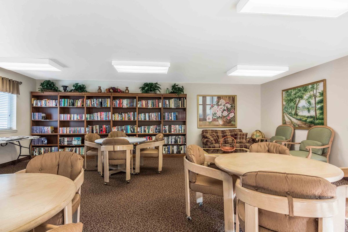 A cozy library with bookshelves, tables, and chairs set up for reading and community gatherings.