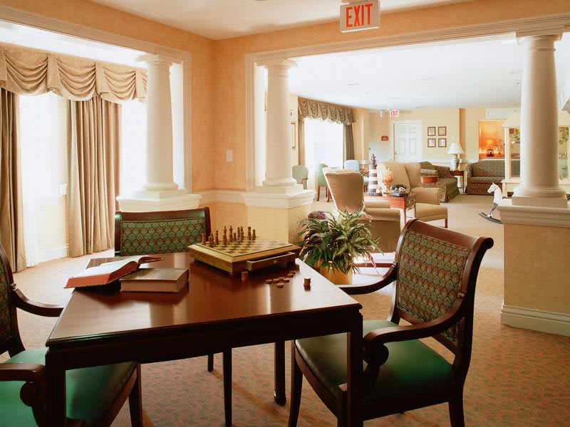 A cozy interior space with a table set for a game of chess, surrounded by comfortable chairs and warm lighting.