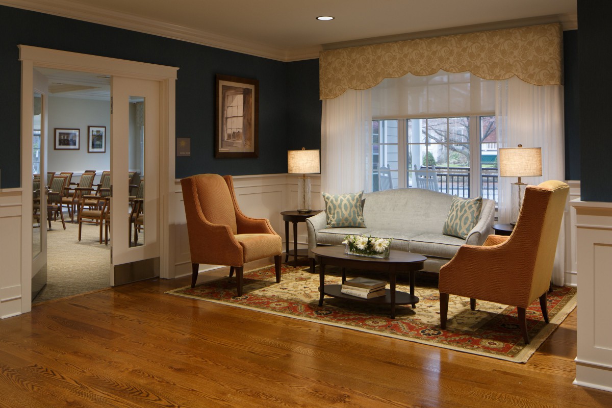 A cozy and elegantly decorated living room featuring a sofa, armchairs, and a coffee table on hardwood flooring.