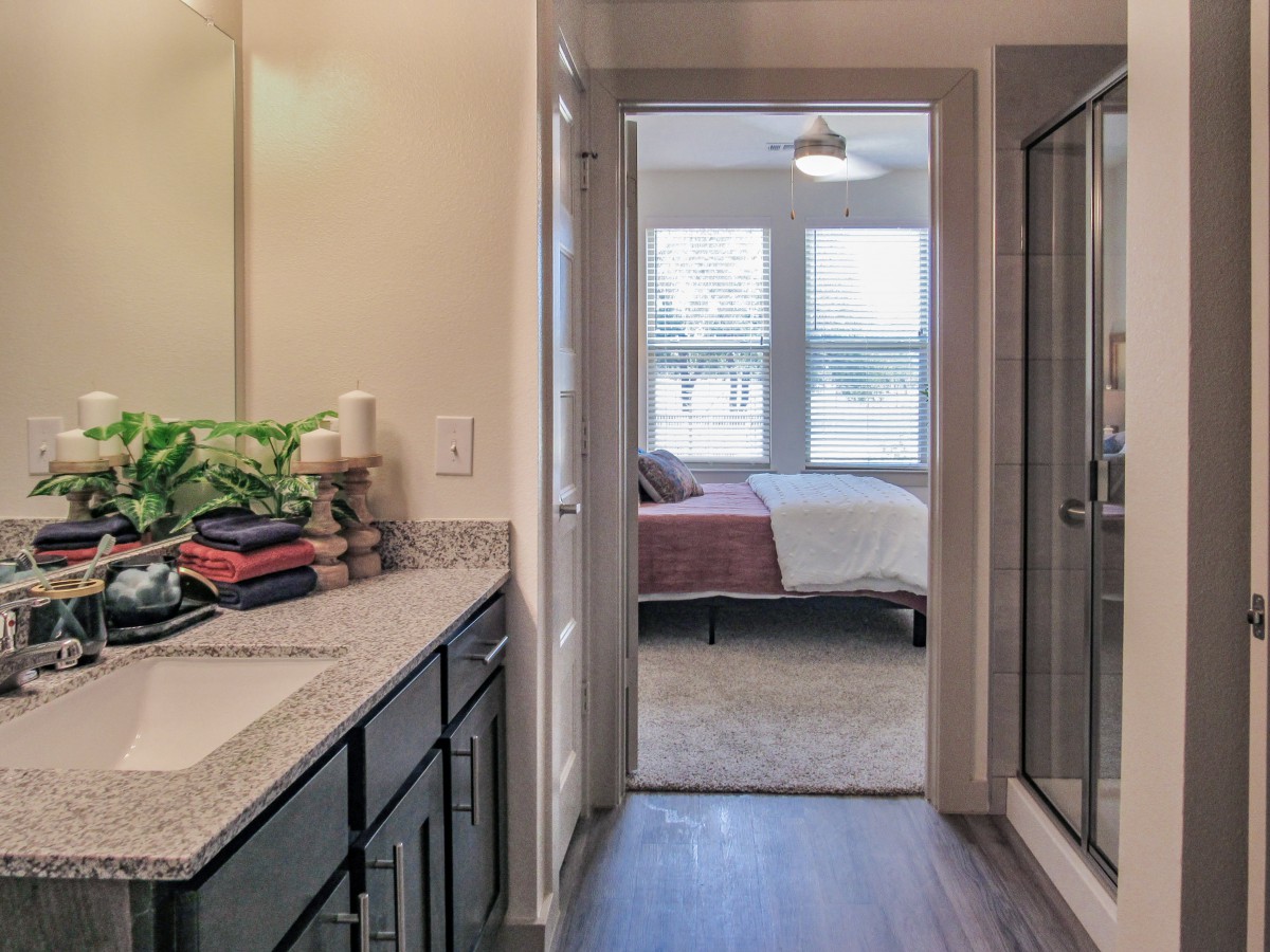 A view from the bathroom leading to a bedroom with ample natural light.