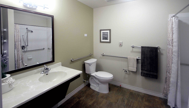A modern bathroom with a sink, toilet, mirror, and wall art, featuring towels hanging on the rail.