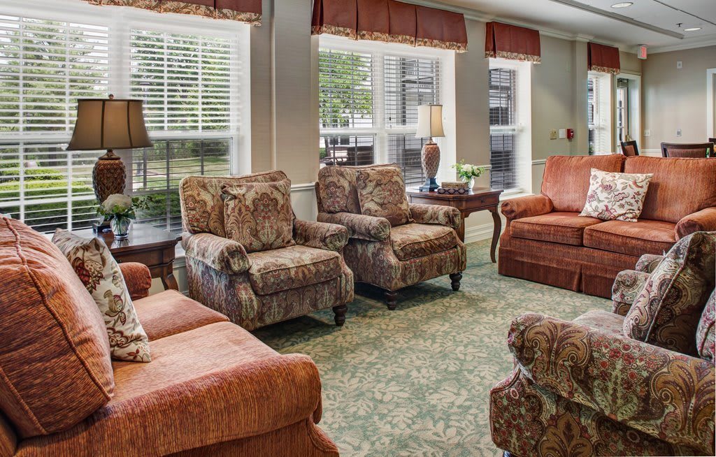 A cozy living room with patterned armchairs and large windows.