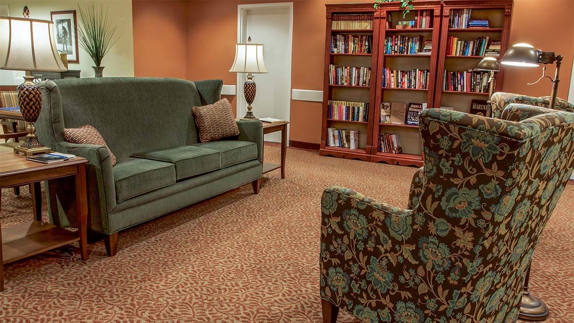 A cozy living room with a sofa, armchair, and a bookshelf filled with books.