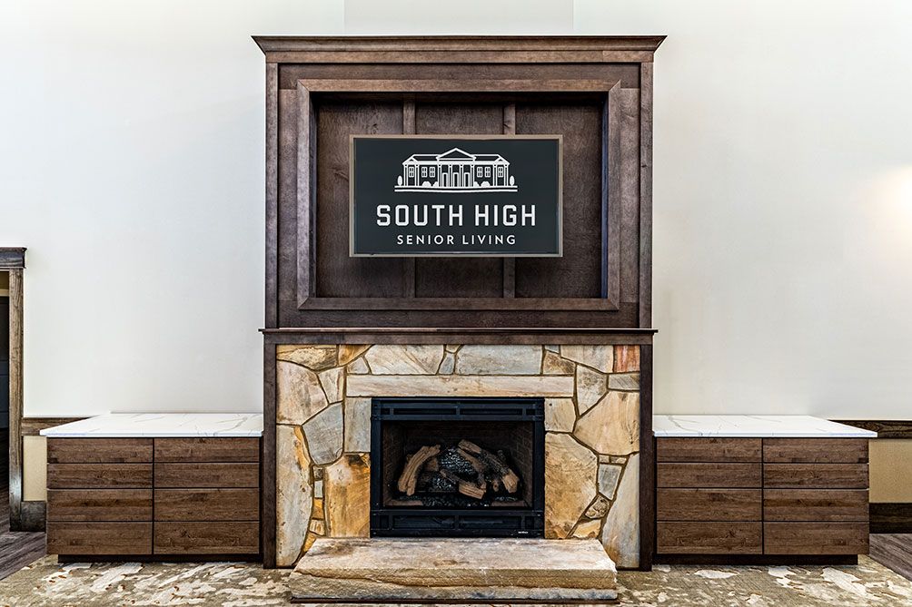 A stone and wood fireplace featuring the 'South High Senior Lounge' sign.